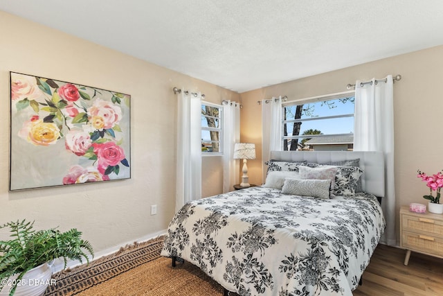 bedroom featuring multiple windows, hardwood / wood-style floors, and a textured ceiling