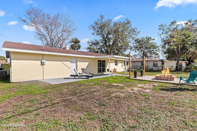 back of house featuring a patio, central AC, a lawn, and a fire pit