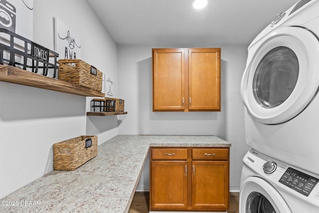 clothes washing area featuring cabinets and stacked washer / dryer