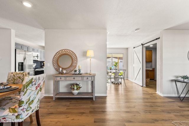 hall with a barn door and dark hardwood / wood-style floors