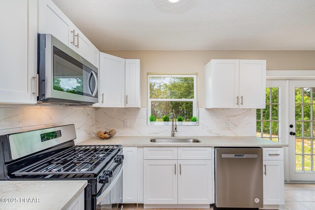 1808 Green Pl, Ormond Beach, FL 32174 - kitchen featuring appliances with stainless steel finishes, a sink, white cabinets, light countertops, and a textured ceiling