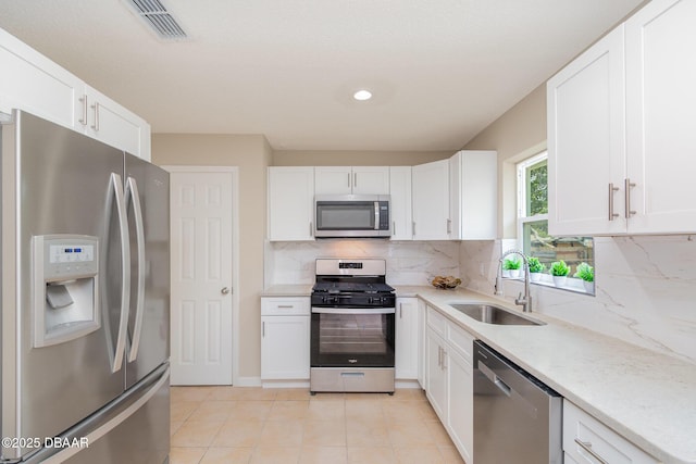 1808 Green Pl, Ormond Beach, FL 32174 - kitchen featuring appliances with stainless steel finishes, a sink, light tile patterned floors, white cabinets, and decorative backsplash