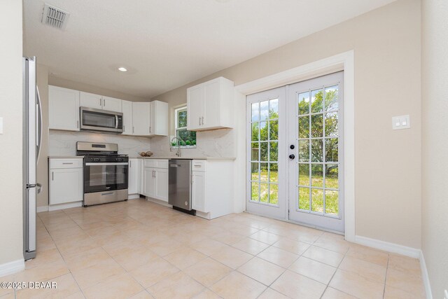 1808 Green Pl, Ormond Beach, FL 32174 - kitchen with stainless steel appliances, french doors, tasteful backsplash, white cabinets, and baseboards