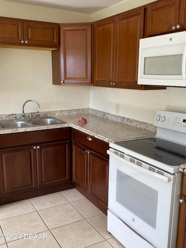 kitchen featuring light tile patterned flooring, white appliances, and sink