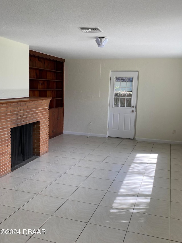 unfurnished living room featuring built in features, light tile patterned flooring, and a textured ceiling