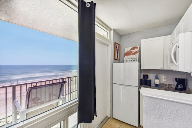 kitchen featuring white cabinets, plenty of natural light, a water view, and white appliances