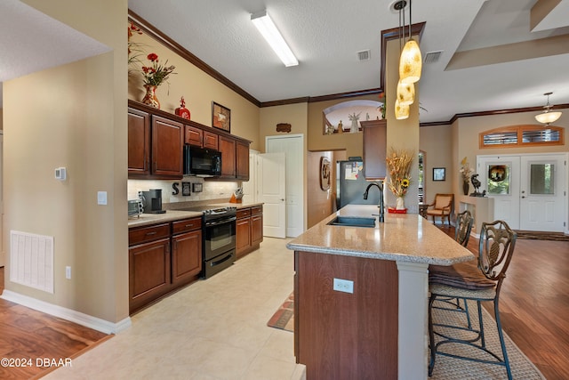 kitchen featuring light stone countertops, sink, light hardwood / wood-style floors, a breakfast bar area, and black appliances