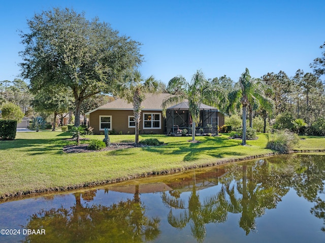 rear view of property with a lanai, a yard, and a water view