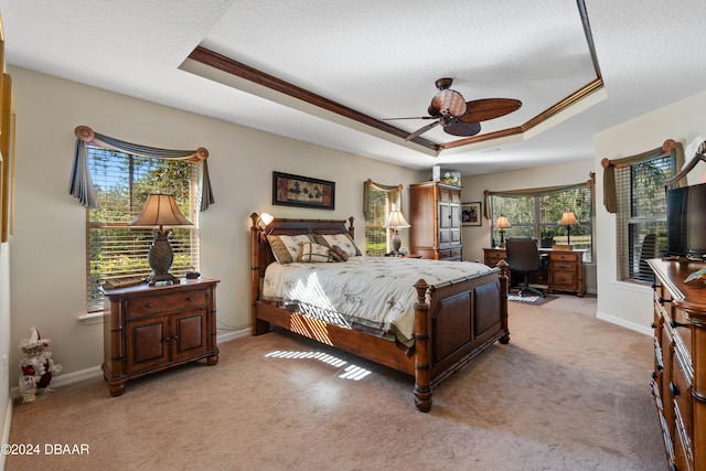 bedroom with a tray ceiling, ceiling fan, and light carpet