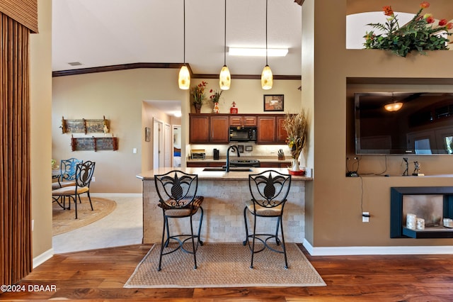 kitchen featuring pendant lighting, crown molding, sink, dark hardwood / wood-style floors, and a breakfast bar area