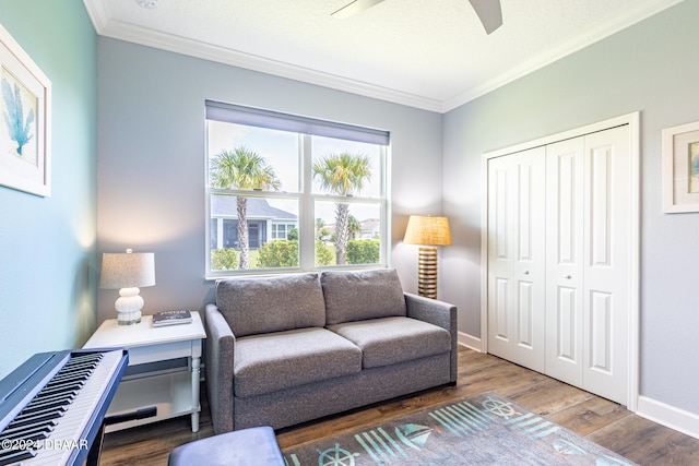 living room with dark wood-type flooring, ceiling fan, and crown molding