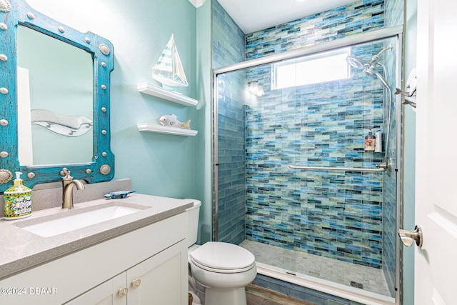 bathroom with a shower with door, vanity, and toilet