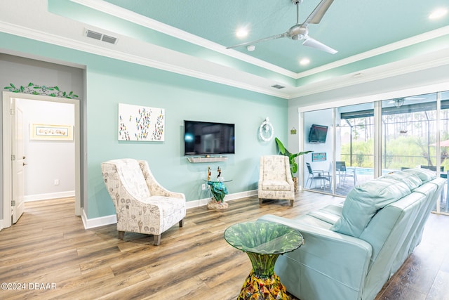 living room featuring a tray ceiling, ornamental molding, ceiling fan, and hardwood / wood-style flooring