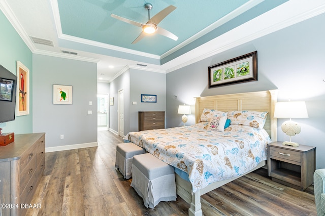 bedroom with dark hardwood / wood-style floors, ceiling fan, a tray ceiling, crown molding, and a closet