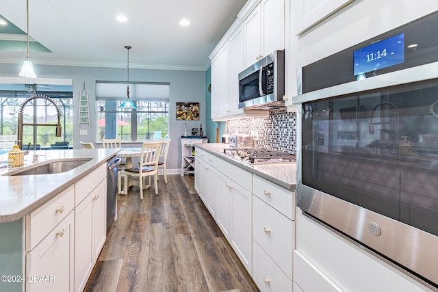 kitchen featuring sink, white cabinetry, ornamental molding, appliances with stainless steel finishes, and pendant lighting