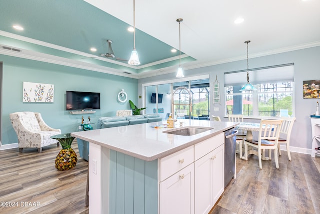 kitchen with pendant lighting, dishwasher, light hardwood / wood-style floors, white cabinets, and a center island with sink