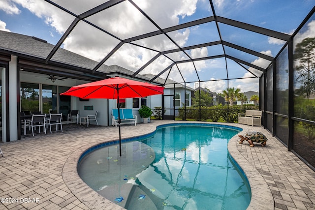 view of swimming pool with ceiling fan, a patio, and glass enclosure