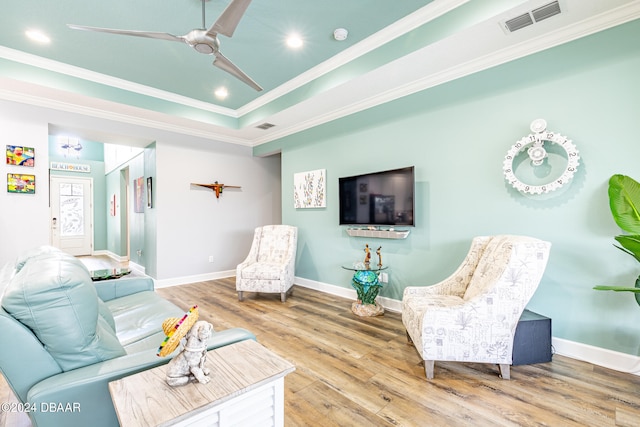 living room with crown molding, ceiling fan, a raised ceiling, and hardwood / wood-style floors