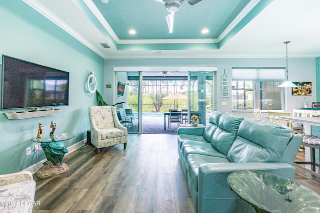 living room featuring hardwood / wood-style flooring, crown molding, ceiling fan, and a tray ceiling