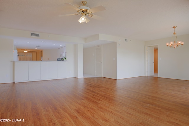 unfurnished living room with ceiling fan with notable chandelier and light hardwood / wood-style flooring