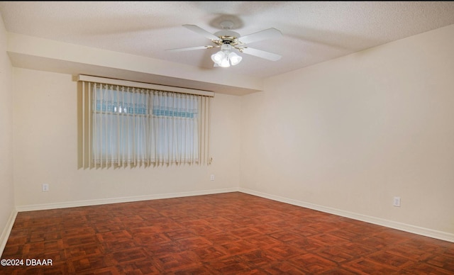 spare room with dark parquet flooring, a textured ceiling, and ceiling fan