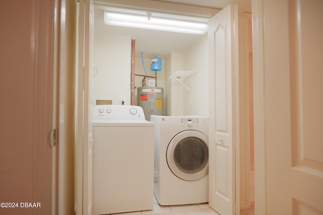 laundry area featuring water heater, light tile patterned floors, and washing machine and clothes dryer