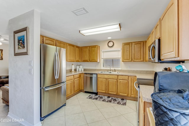 kitchen with stainless steel appliances, light tile patterned flooring, and light brown cabinetry