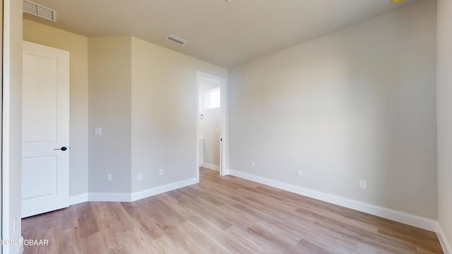 empty room with light wood-type flooring, visible vents, and baseboards