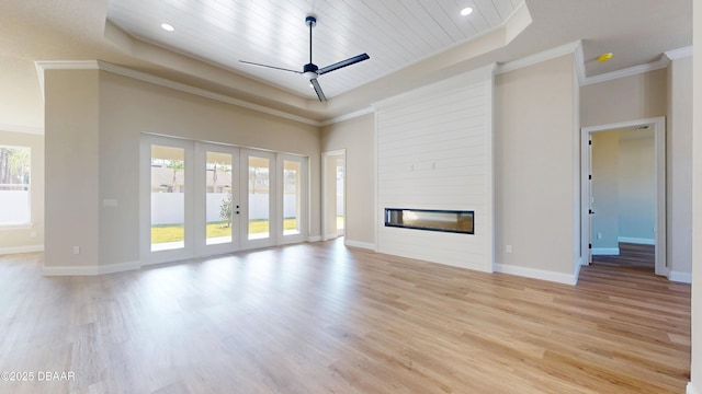 unfurnished living room featuring a large fireplace, a raised ceiling, and crown molding