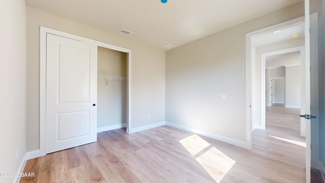 unfurnished bedroom featuring baseboards, visible vents, and light wood finished floors