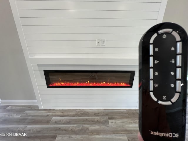 detailed view of a glass covered fireplace, wood finished floors, and baseboards
