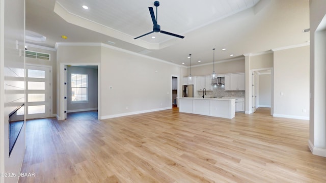 unfurnished living room with ceiling fan, light wood finished floors, visible vents, and baseboards