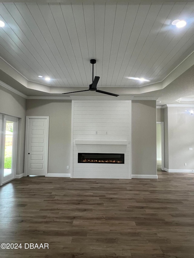 unfurnished living room featuring a tray ceiling, crown molding, a fireplace, dark wood-type flooring, and wooden ceiling