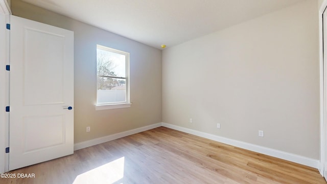 unfurnished room with baseboards and light wood-style floors