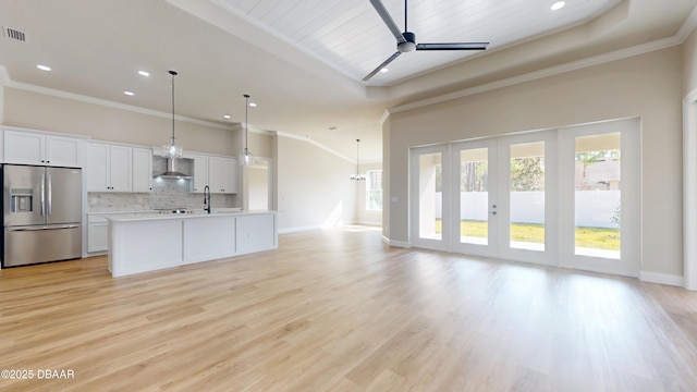 unfurnished living room featuring light wood-type flooring, ceiling fan, ornamental molding, and baseboards