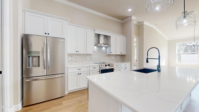 kitchen with light stone counters, white cabinets, appliances with stainless steel finishes, wall chimney exhaust hood, and pendant lighting