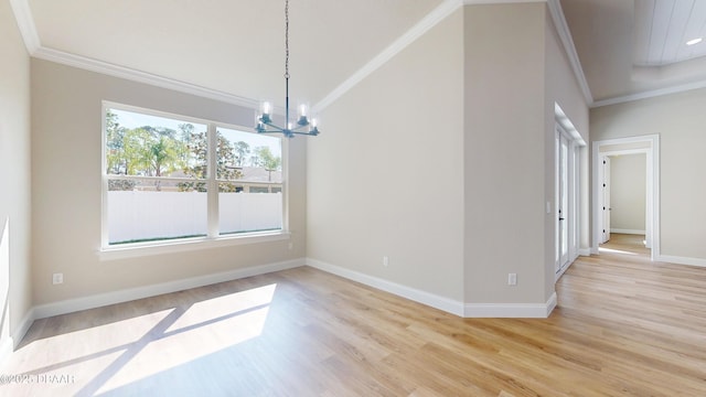 unfurnished dining area with light wood finished floors, baseboards, crown molding, and an inviting chandelier