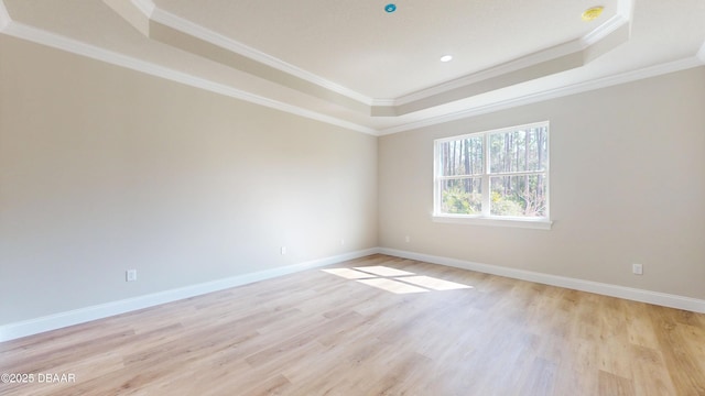 unfurnished room with light wood-type flooring, baseboards, a tray ceiling, and ornamental molding