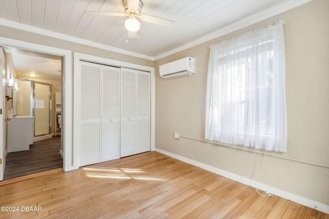 unfurnished bedroom with ornamental molding, a wall unit AC, ceiling fan, hardwood / wood-style floors, and a closet