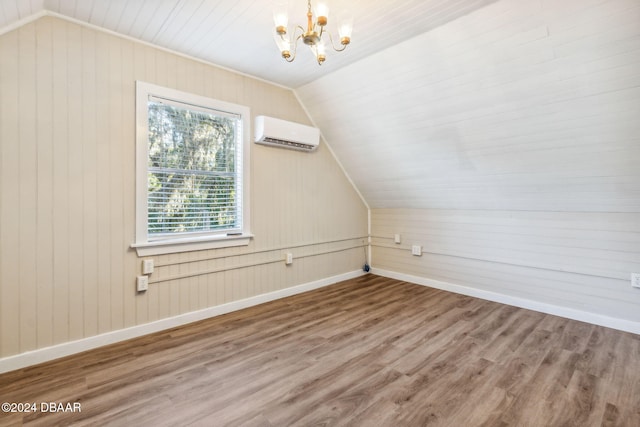 additional living space with an AC wall unit, wood walls, wood-type flooring, and vaulted ceiling