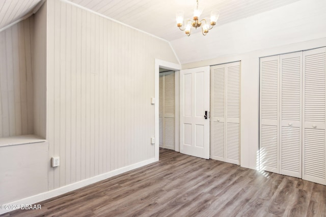 unfurnished bedroom featuring multiple closets, an inviting chandelier, wood-type flooring, lofted ceiling, and wooden walls