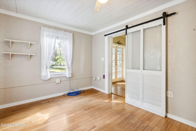 unfurnished bedroom featuring ceiling fan, wooden ceiling, a barn door, wood-type flooring, and ornamental molding