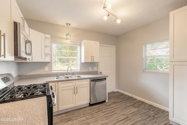 kitchen with stainless steel appliances, white cabinetry, hanging light fixtures, and sink