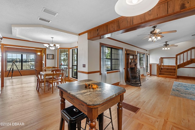 dining room featuring crown molding, light wood-type flooring, and a textured ceiling