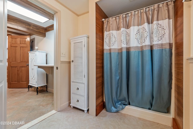 bathroom with walk in shower, crown molding, beam ceiling, tile patterned flooring, and wood walls