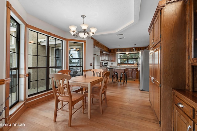 dining room featuring light wood-type flooring, a textured ceiling, a wealth of natural light, and a chandelier