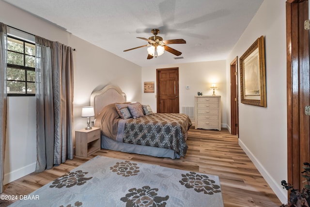 bedroom with hardwood / wood-style floors, a textured ceiling, and ceiling fan