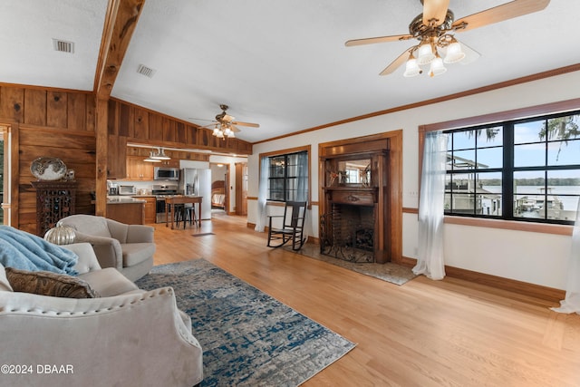 living room featuring wood walls, lofted ceiling with beams, crown molding, light hardwood / wood-style flooring, and ceiling fan