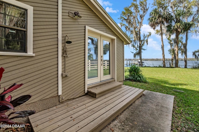 doorway to property featuring french doors, a yard, and a water view