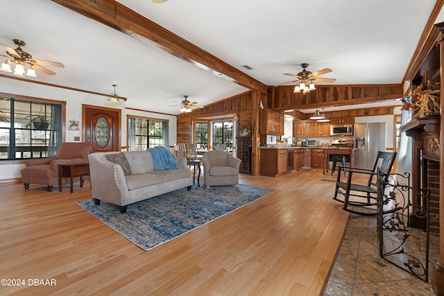 living room featuring lofted ceiling with beams, crown molding, wooden walls, and light hardwood / wood-style flooring